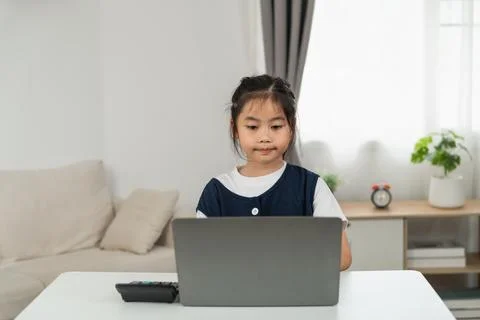 Young girl sitting at table using laptop computer with focused expression i.. Stock Photos