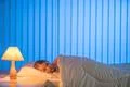 The young girl sleeping on the bed. Evening night time Photo