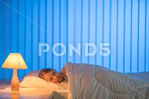 The young girl sleeping on the bed. Evening night time Stock Photos