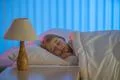 The young girl sleeping on the bed. Evening night time Photo