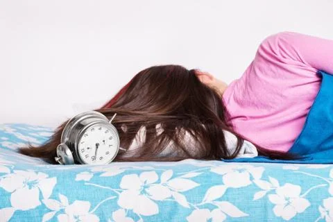 Young girl sleeping while the clock is ringing Stock Photos