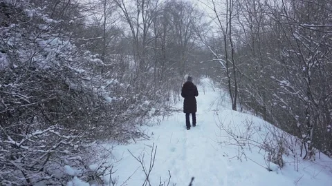 A young girl slowly walking path covered with deep snow in outdoors. She is Stock Footage 147130852
