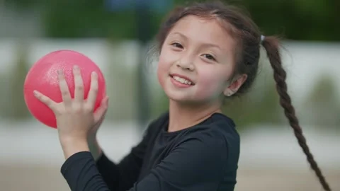 Young girl smiles while playing with a pink ball Stock Footage 340448768