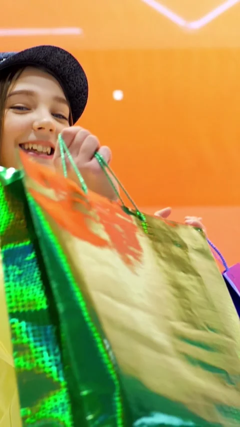 Young girl smiling joyfully while holding shopping bags in vibrant retail Video stock 313259682