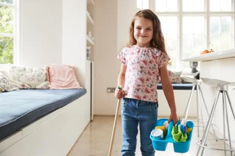 Young girl standing at home with broom and cleaning products Stock Photos