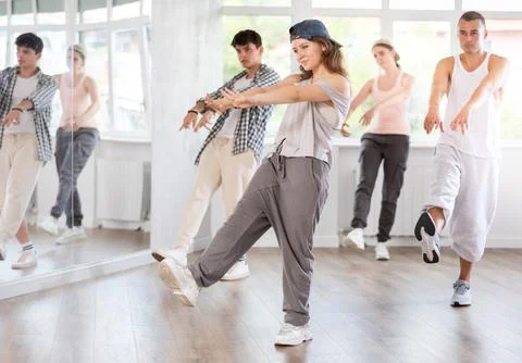 Young girl standing performs basic hip hop movements in front of group of Stock Photos