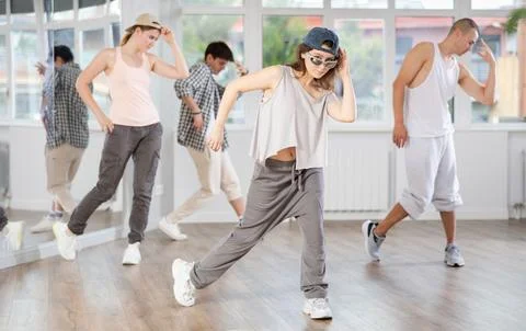 Young girl standing performs basic hip hop movements in front of group of Stock Photos