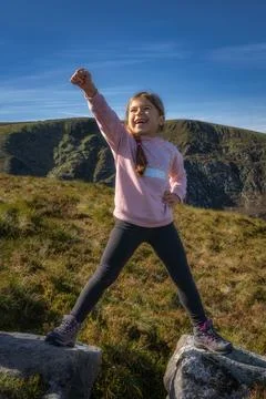 Young girl standing in split on two rocks with raised hand in triumph and vic Stock Photos