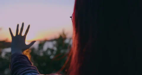 A young girl at sunset is playing with the rays of the sun passing through her h Stock Footage 159129224