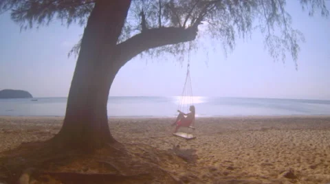 Young girl swinging on a beach at sunset time, relaxing on a tropical beach Stock Footage 59369711