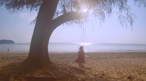 Young girl swinging on a tropical beach at sunset time in Thailand Stock Footage 59371395