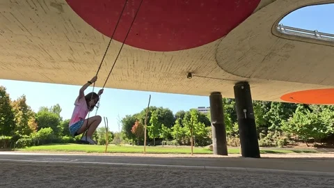 Young girl swinging while standing under a bridge Stock Footage 297083597