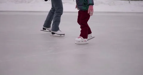 Young girl taking first steps skating on ice rink wearing warm winter clothing Video stock 319791442