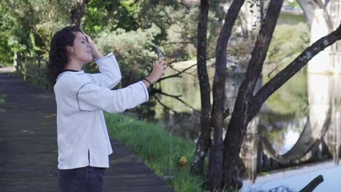 Young girl taking a selfie while grooming herself in a natural environment with Stock Footage 254599371