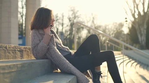 Young girl talking on the phone while sitting on the stairs slow motion Stock Footage 75450460