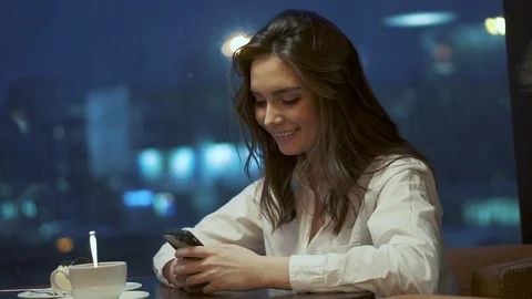 Young girl is texting a message on the smartphone while sitting in a cafe on the Stock Footage 101790965