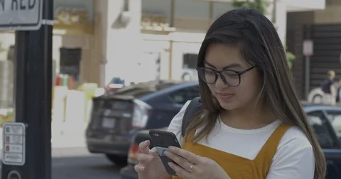 Young Girl Texts at Intersection with Traffic in City Stock Footage 114704364