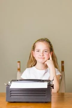Young girl thinking while working on old typewriter Stock Photos