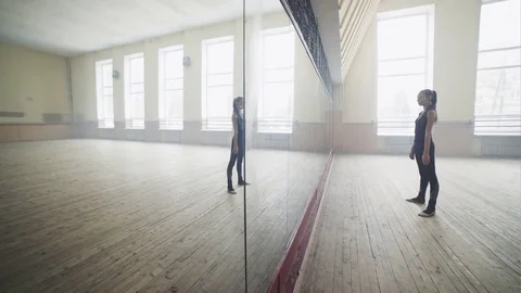 A young girl trained in the complex modern acrobatic dancing before a mirror in Stock Footage