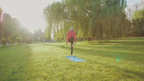 Young girl training gymnastics in the park among the sun glare 4K Stock Footage