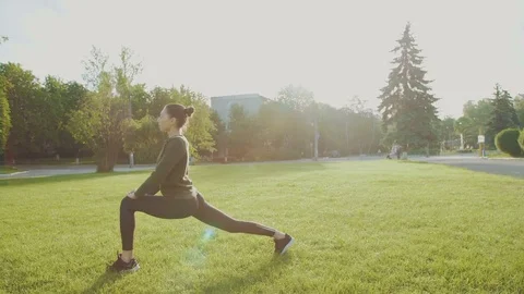 Young girl training yoga in the park among the sun glare 4K Stock Footage