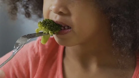 Young girl tries broccoli and hates it, children can't stand raw vegetables Stock Footage