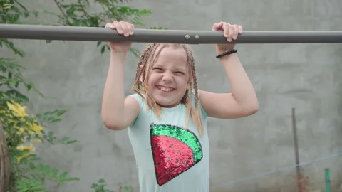 Young girl tries to pull herself up on crossbar. Video stock 199798772
