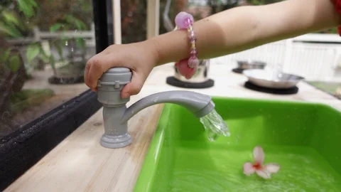 Young girl turning on outdoor play kitchen tap, slow motion. Stock Footage