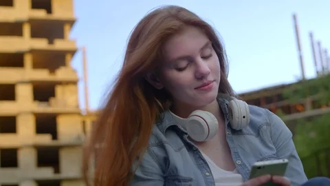 Young Girl Typing on Smartphone while Sitting on Skateboard Outdoors Видео 96319932