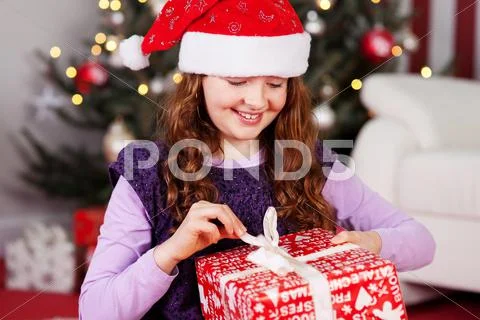 Young girl unwrapping her christmas present Stock Photos