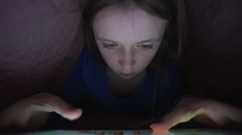 A young girl uses a digital tablet under the covers Stock Footage 44114875