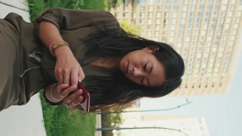 Young girl uses smartphone while sitting on modern buildings background Stock Footage 227109366