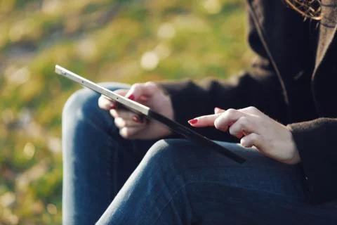 A young girl uses a tablet while in the megapolis park Stock Photos