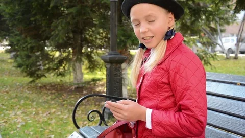Young girl using app on smartphone sits on bench in autumn in city park Stock Footage 81335839