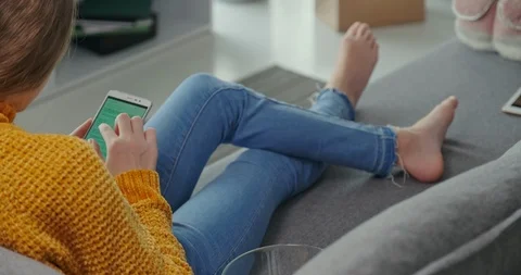 Young girl using cell phone, she is online, 11 years old, sitting on sofa Stock Footage 127321153