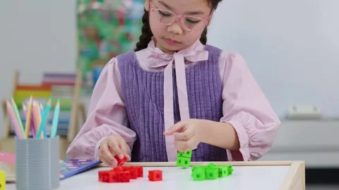 Young Girl Using Colorful Math Manipulative Blocks at School Desk Stock Footage 327770908