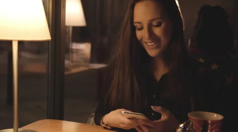Young girl using her mobile phone in Cafe in the Evening 4K 스톡 동영상 46594921