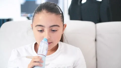 Young girl using a nebulizer inhaler device with mist shooting out of the Stock-Footage