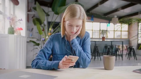 Young girl using online app on mobile in headphones listening music and browsing Stock Footage 103285612