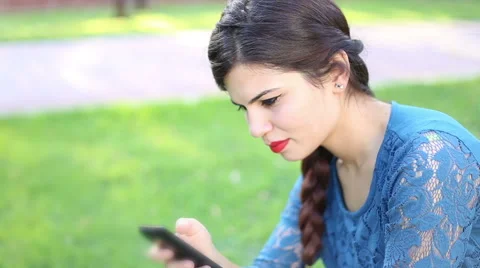 Young girl using smart phone in park Stock Footage 55392995