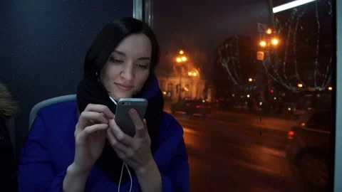 Young girl using smart phone during bus ride in evening in city. Car traffic Stock Footage 83872624