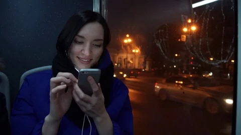 Young girl using smart phone during bus ride in evening in city. Car traffic Stock Footage 83872676