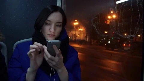 Young girl using smart phone during bus ride in evening in city. Car traffic Stock Footage 83872771