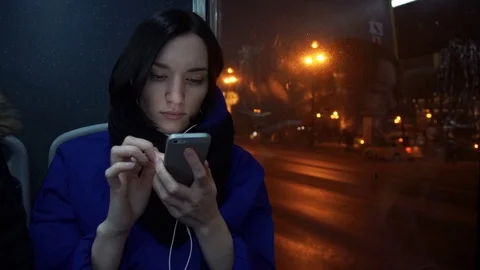 Young girl using smart phone during bus ride in evening in city. Car traffic Stock Footage 83872801