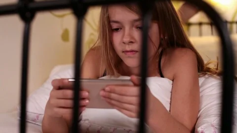 Young girl using smartphone lying in bed Stock Footage 80006396