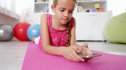 Young girl using smartphone lying on the floor Stock-Footage 80144925
