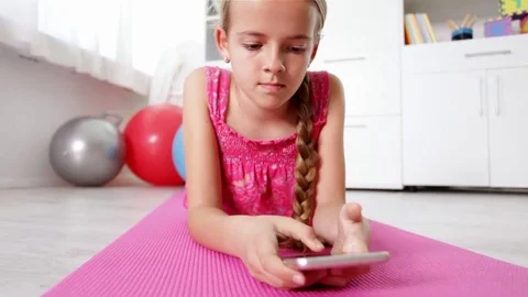 Young girl using smartphone lying on the floor Video stock 80353690
