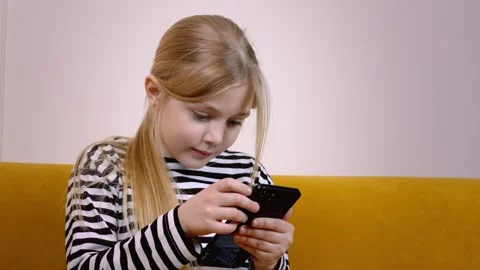 Young girl using smartphone while sitting on yellow sofa Stock Footage 315876727