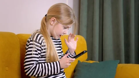 Young girl using smartphone while sitting on yellow sofa 库存影片 315876744