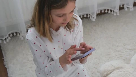 Young girl using smartphone while sitting on carpet  home. Stock Footage 331659340